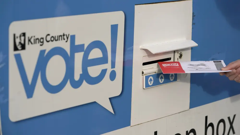 FILE - A person puts their ballot in a drop box on Oct. 27, 2020, at a library in Seattle. A Washington state judge on Friday, June 7, 2024, turned back an attempt by GOP backers of three initiatives to keep the fiscal impact of the measures off the November ballot. (AP Photo/Ted S. Warren, File)