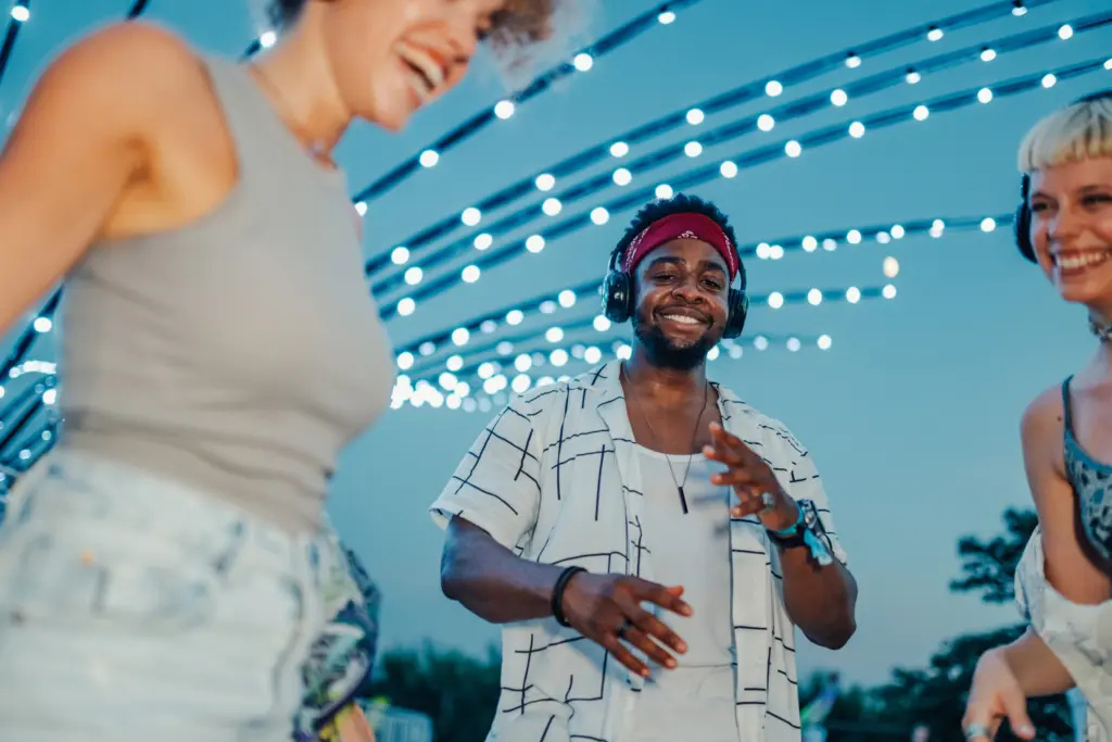 friends-enjoying-music-festival-dancing-under-string-lights