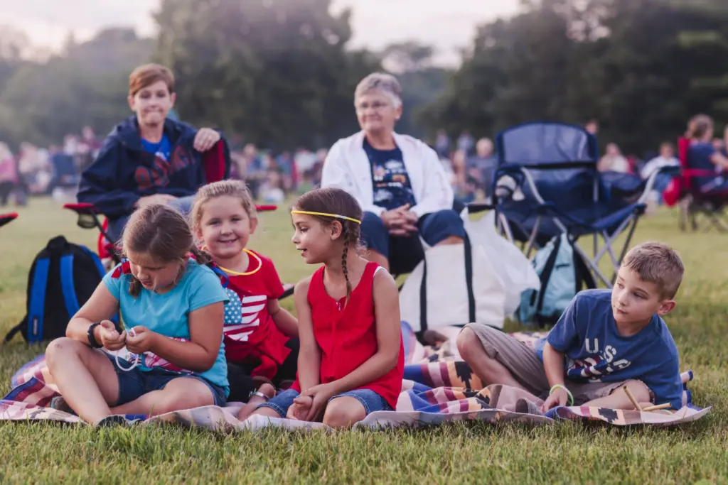 group-of-adults-and-children-sitting-outdoors-during-4th-july-celebrations