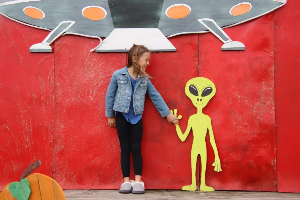 girl-with-red-backdrop-holding-aliens-hand-spacesh-2024-11-26-02-03-22-utc