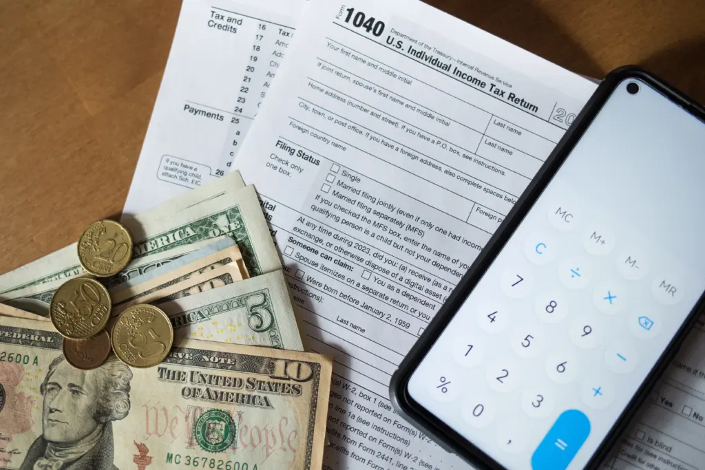 tax-refund-form-1040-money-dollars-and-phone-with-open-calculator-on-table