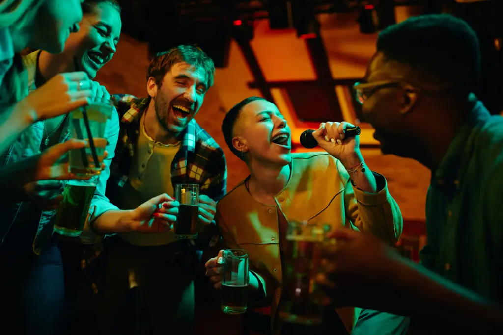 cheerful-friends-having-fun-while-singing-karaoke-during-their-night-out-in-a-pub