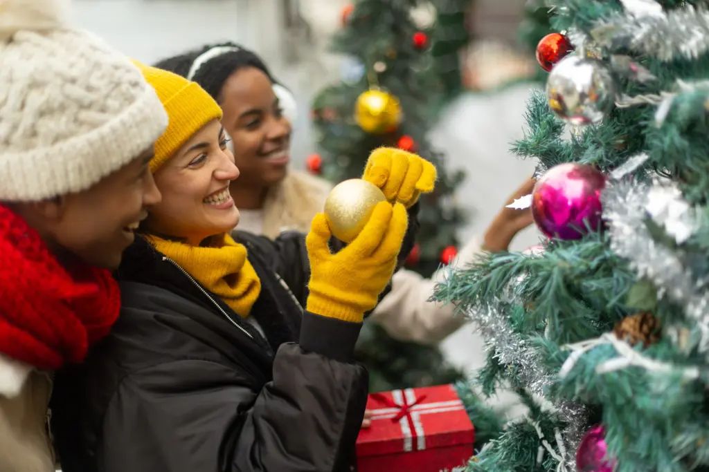 friends-decorating-christmas-tree-with-golden-ball-ornament