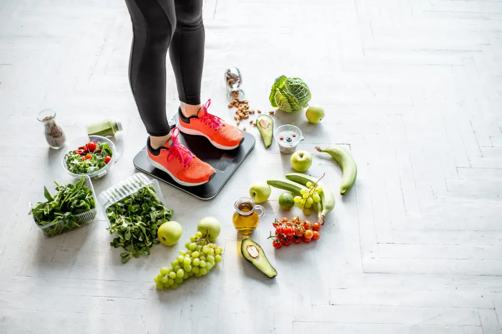 sports-woman-weighing-with-healthy-food-around