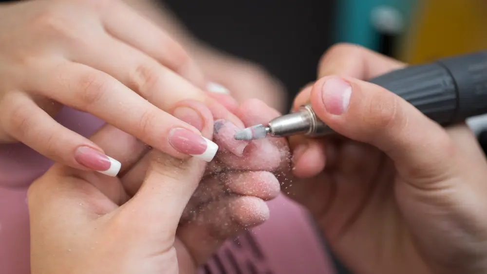 shot-of-master-uses-an-electric-machine-to-remove-the-nail-polish-during-manicure-in-the-salon