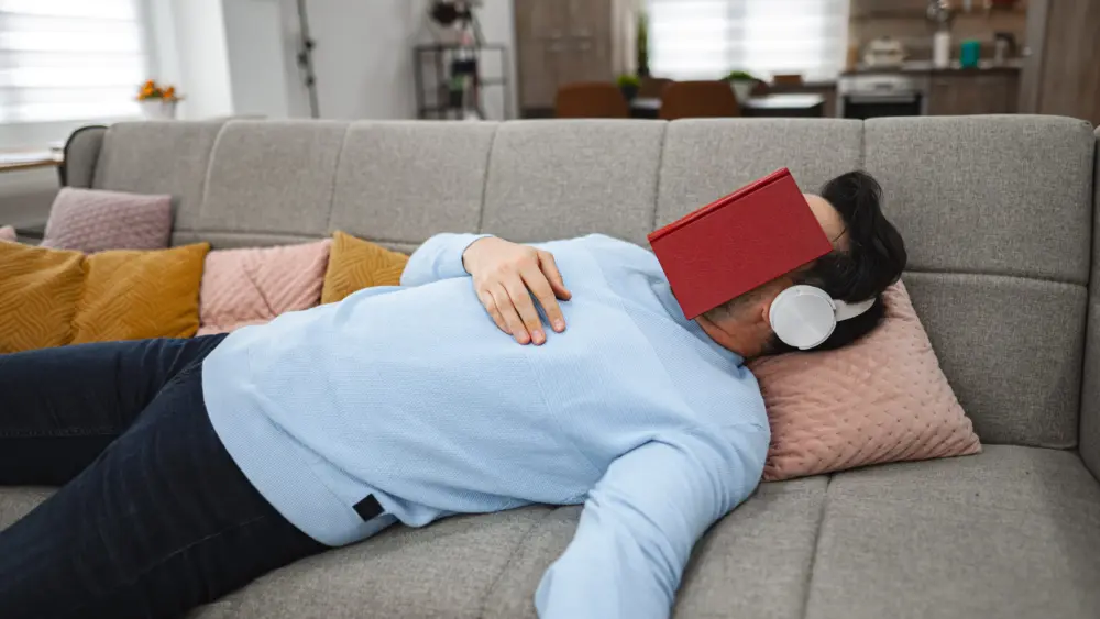 person-laying-on-couch-with-book-on-head