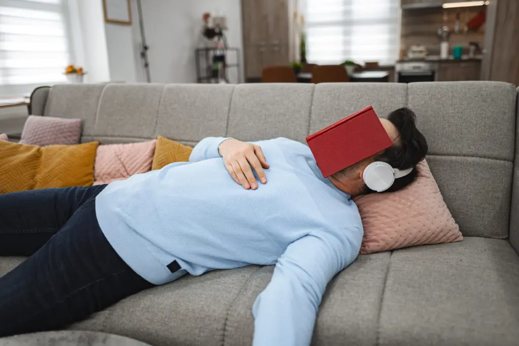 person-laying-on-couch-with-book-on-head