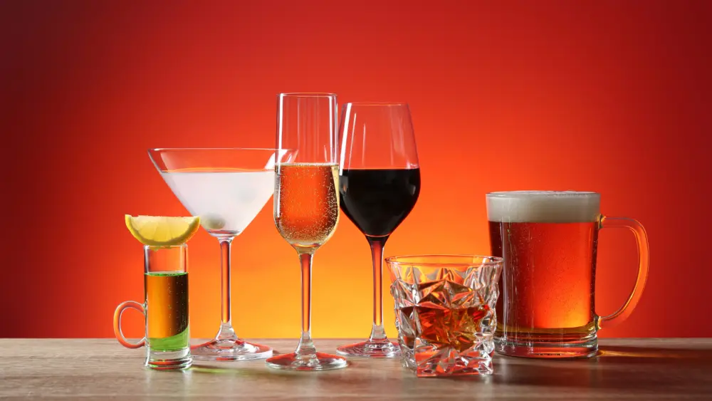 different-alcohol-drinks-on-wooden-table-against-red-background