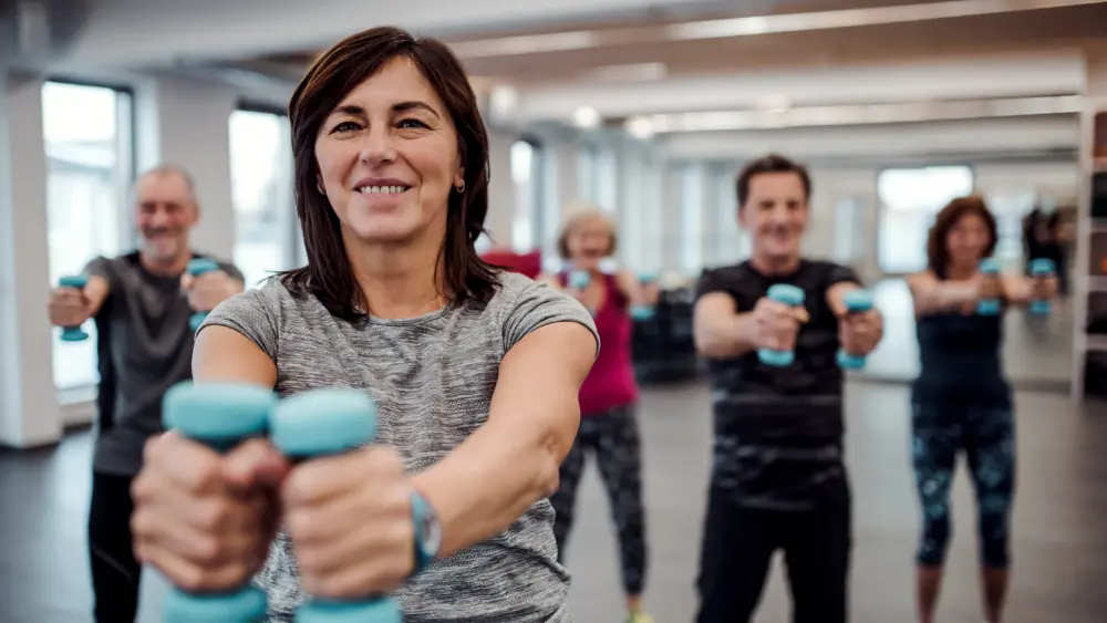 group-of-cheerful-seniors-in-gym-doing-exercise-with-dumbbells
