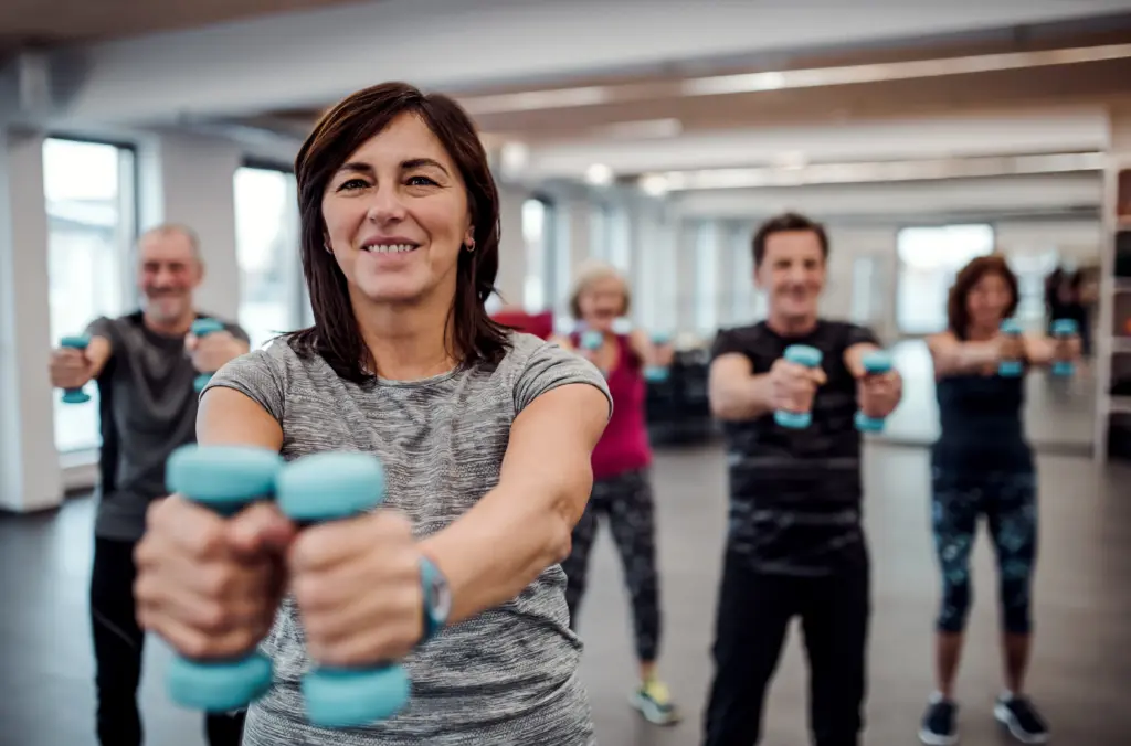 group-of-cheerful-seniors-in-gym-doing-exercise-with-dumbbells
