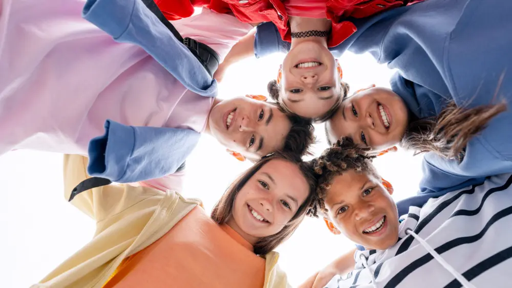diverse-teenagers-smiling-forming-a-huddle-looking-down