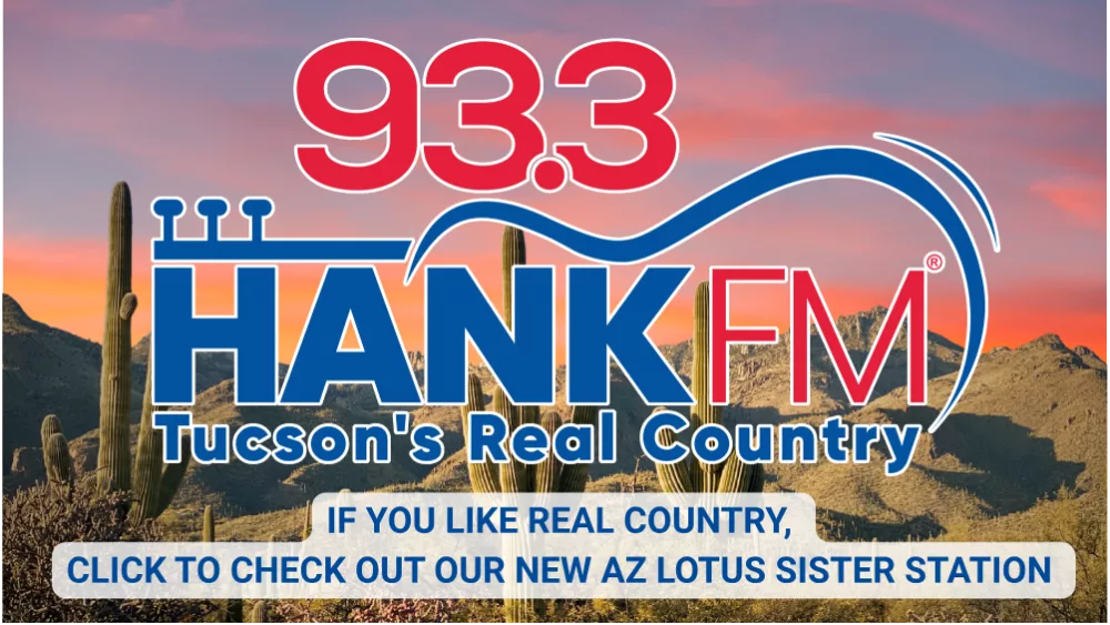 Promotional image for 93.3 Hank FM, Tucson's Real Country radio station. The logo features bold red and blue text with a stylized musical staff and cowboy hat motif. The background shows a scenic desert landscape with cacti and mountains at sunset. A message at the bottom reads: "If you like real country, click to check out our new AZ Lotus sister station.