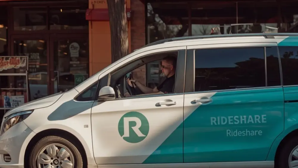 A white mini-van with "Rideshare" on the side written in green.