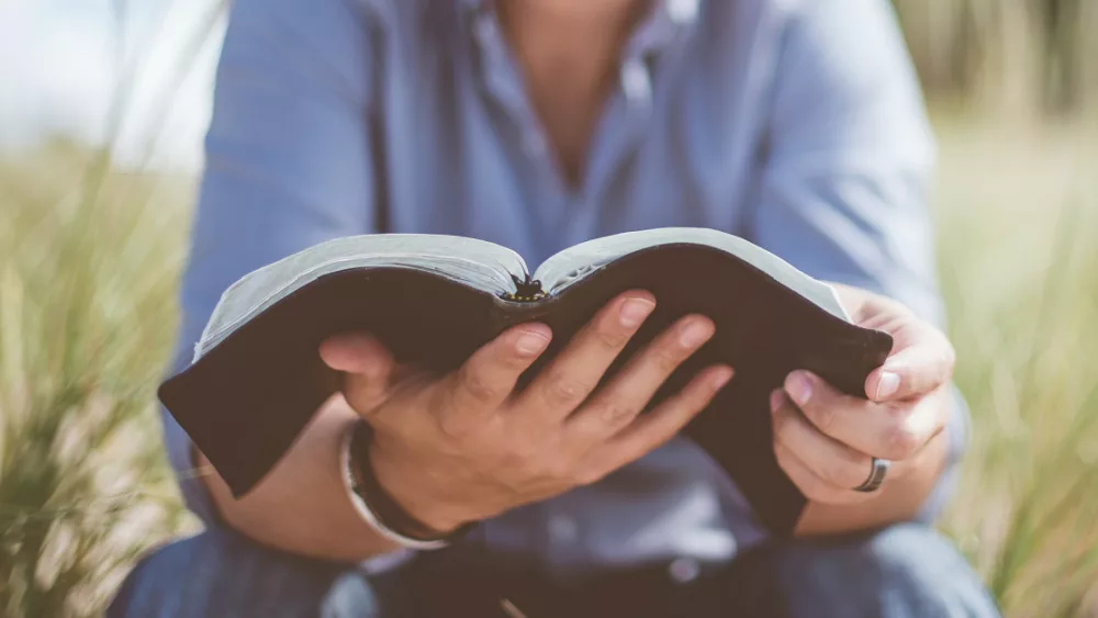 24686-man-holding-bible-ben-white-unsplash-387172