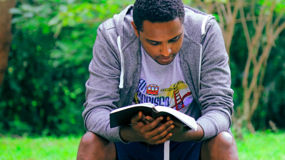 11508-african-american-man-reading-book-outdoors-un126131