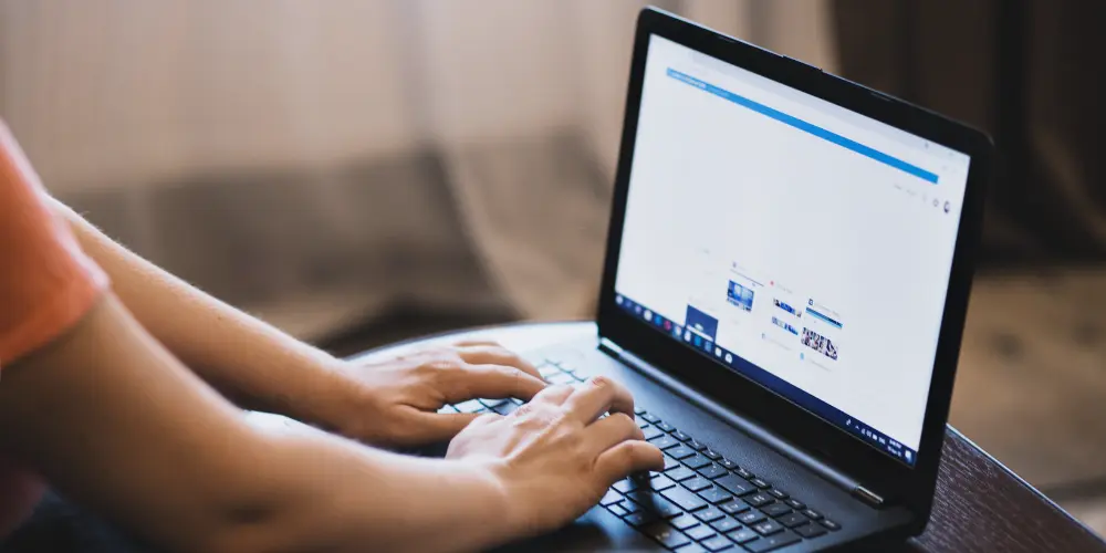 A computer user typing on their laptop.