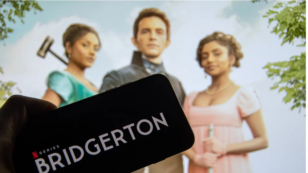The logo of the new Netflix series "Bridgerton" on the display of a smartphone in front of the TV