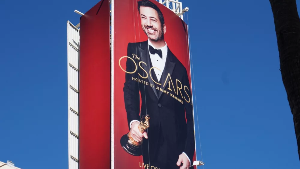 Oscar billboard featuring host Jimmy Kimmel and a golden statue on a red background against the blue sky
