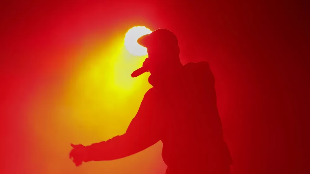 Silhouette of rap singer with microphone in hand. Rapper performing on concert.
