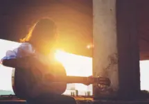 Candid silhouette woman chill play acoustic guitar musician Artists female sad mood activity music at balcony flare lighting sunset background