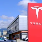 Tesla office^ American company^ electric car manufacturer Elon Musk^ company logo on red stand^ alternative energy development concept^ electric vehicle production^ Innsbruck^ Austria - June 2022