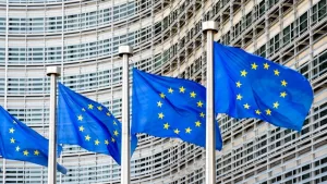 A row of flags of the European Union flying in the wind in front of the Berlaymont building^ seat of the European Commission in Brussels^ Belgium.