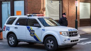 A uniformed Philadelphia Police officer stands beside a police vehicle. PHILADELPHIA^ PA - JANUARY 1^ 2015