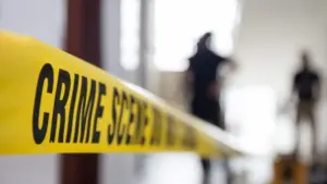 crime scene tape in building with blurred forensic team background