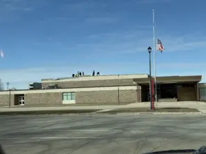 Workers diligently work to make repairs to the Hampton-Dumont High School roof Friday (3/13/26) following wind damage ahead of a forecasted weekend winter storm. Photo credit: RadioOnTheGo News