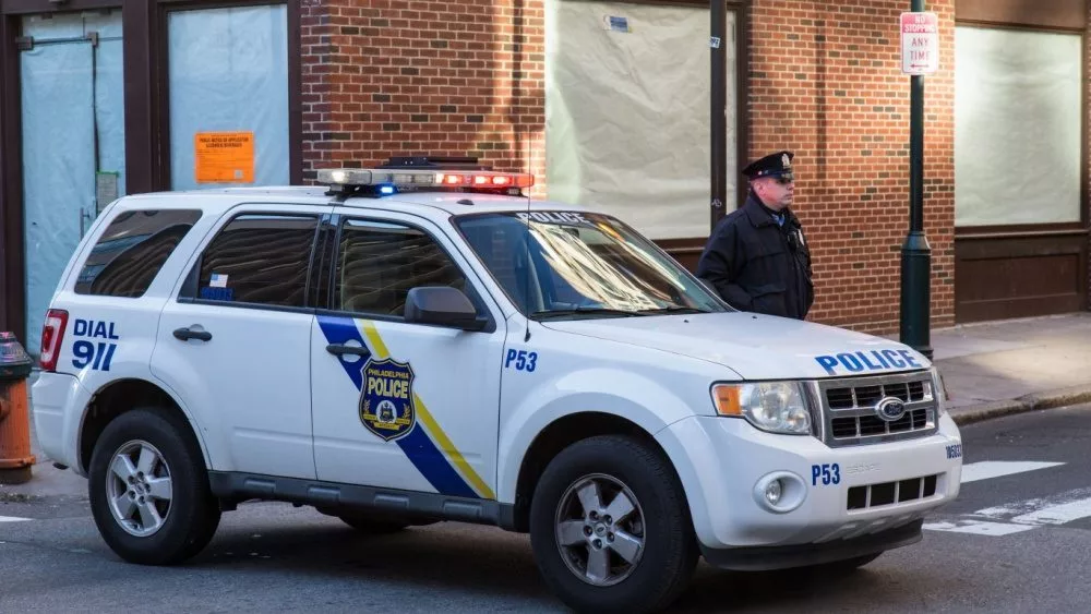 A uniformed Philadelphia Police officer stands beside a police vehicle. PHILADELPHIA^ PA - JANUARY 1^ 2015