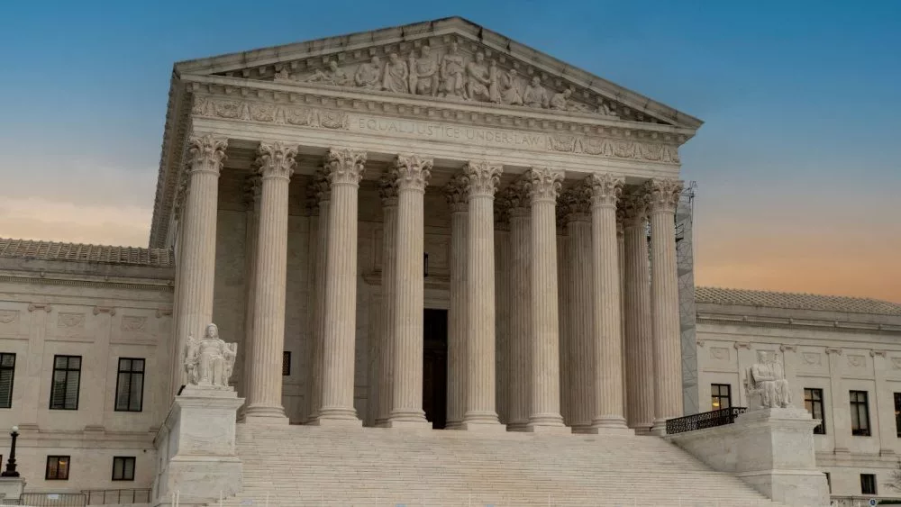 Greek classical architecture of the United States Supreme Court building with sunrise in background.