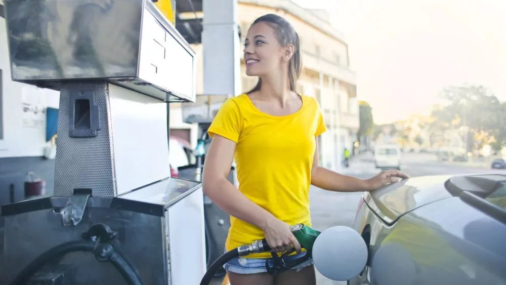 Photo shows teen pumping gas at gas station.