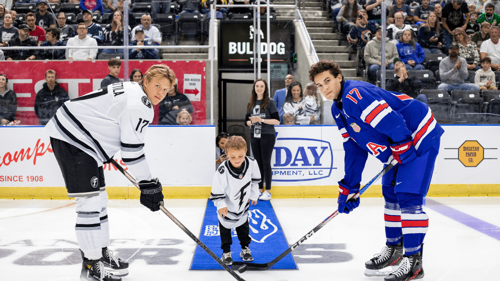 Beau Demers^ son of Chad and Danika Demers^ dropped the ceremonial first puck at Saturday night's Fargo Force hockey game against the US NTDP Under 18 program. Chad is a former Grafton-Park River Spoiler hockey player^ and a former player and coach for the Fargo Force. The team raised more than $60^000 for the Demers family Saturday night as he continues his battle with brain cancer. Participating in the faceoff are Fargo Force forward Reid Daavettila^ left^ and U.S. U-18 forward Andrew O'Neill / photo courtesy of Marissa Shiock