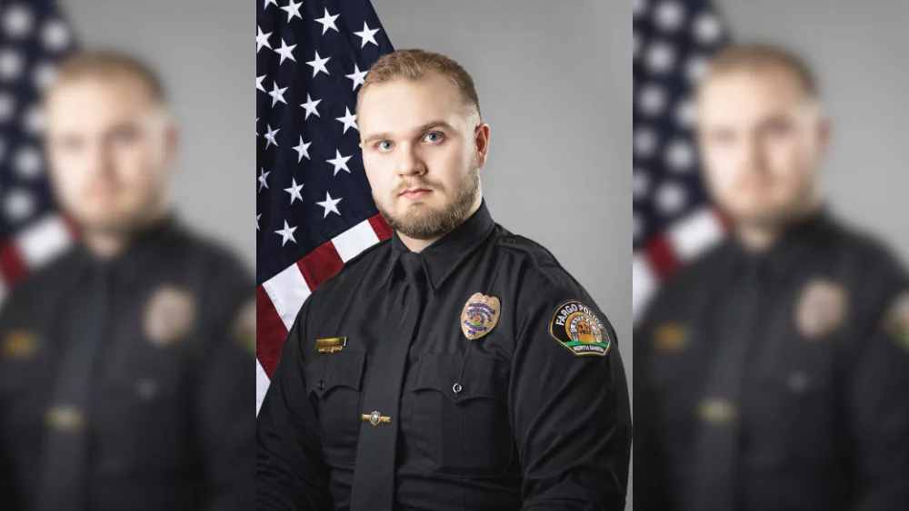 Fargo Police officer in front of a flag