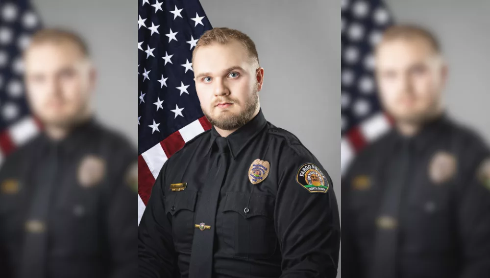 Fargo Police officer in front of a flag