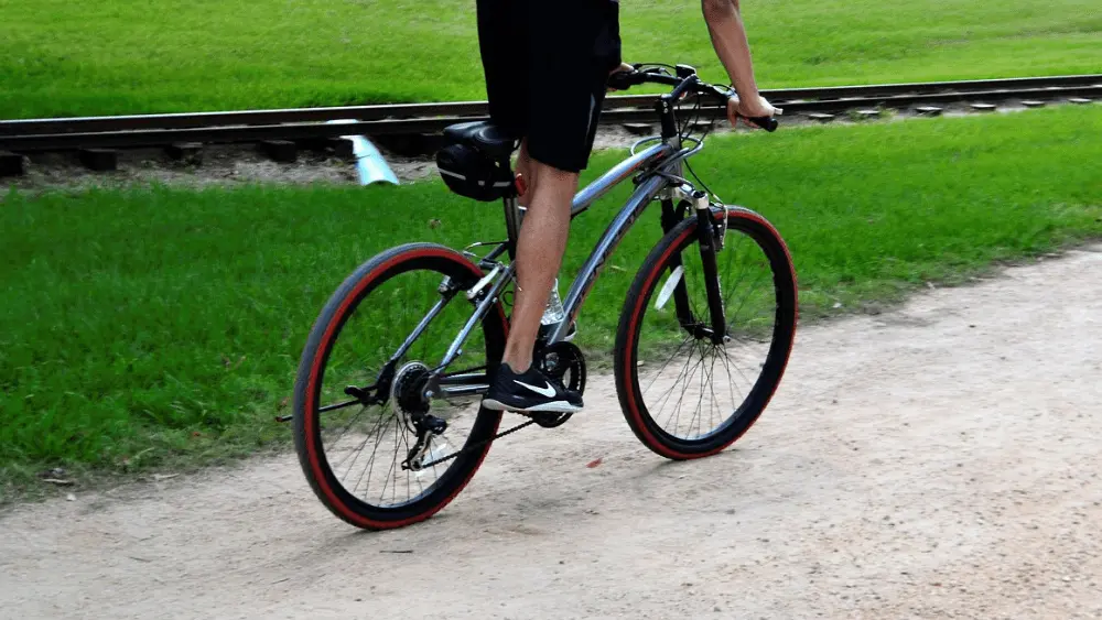 Image of lower half of person riding a mountain bike on a dirt road