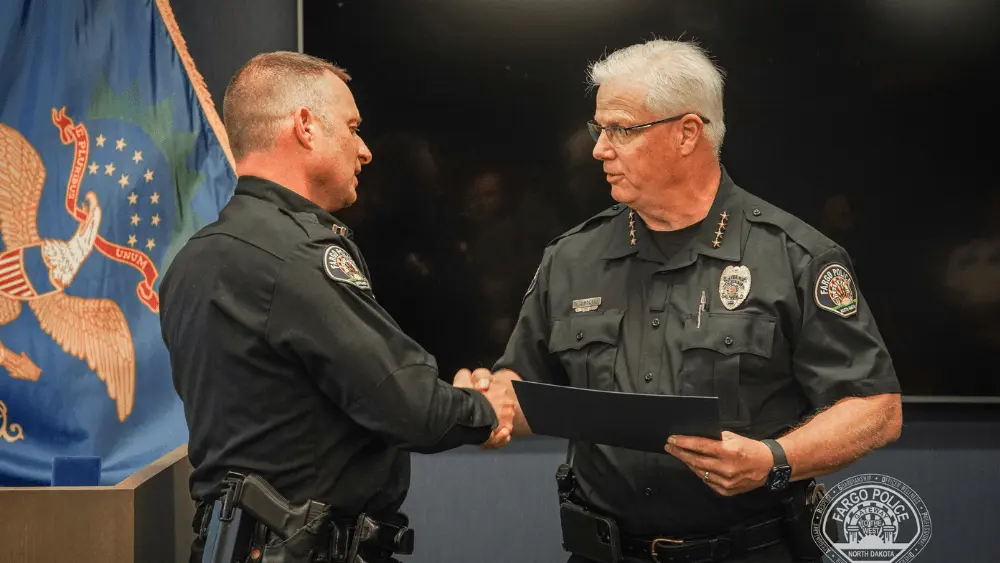 Image of Fargo Police Captain Bill Ahlfeldt shaking Police Chief David Zibolski's hand on his final day with FPD