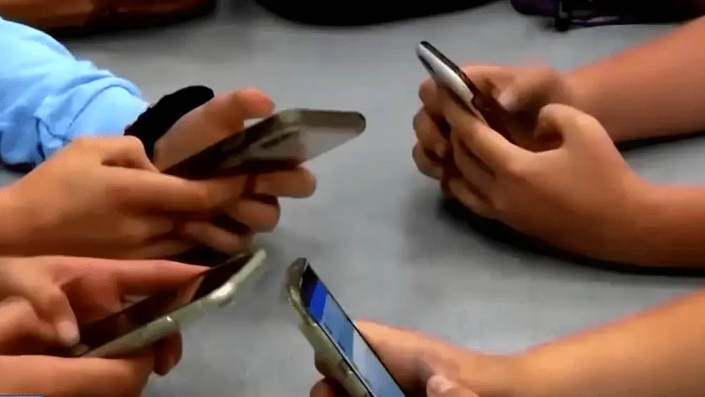 Image of kids holding cell phones at a table