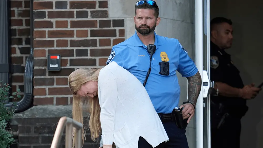 Image of woman hanging her head holding on to a railing as an officer stands by outside the Annunciation Catholic School