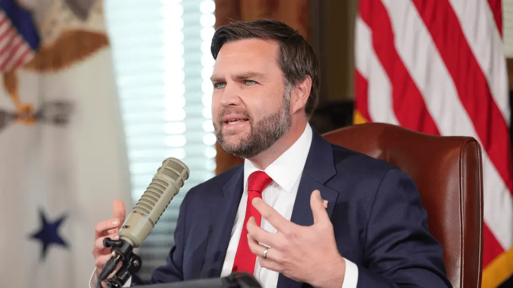 Image of JD Vance behind a microphone hosting the program