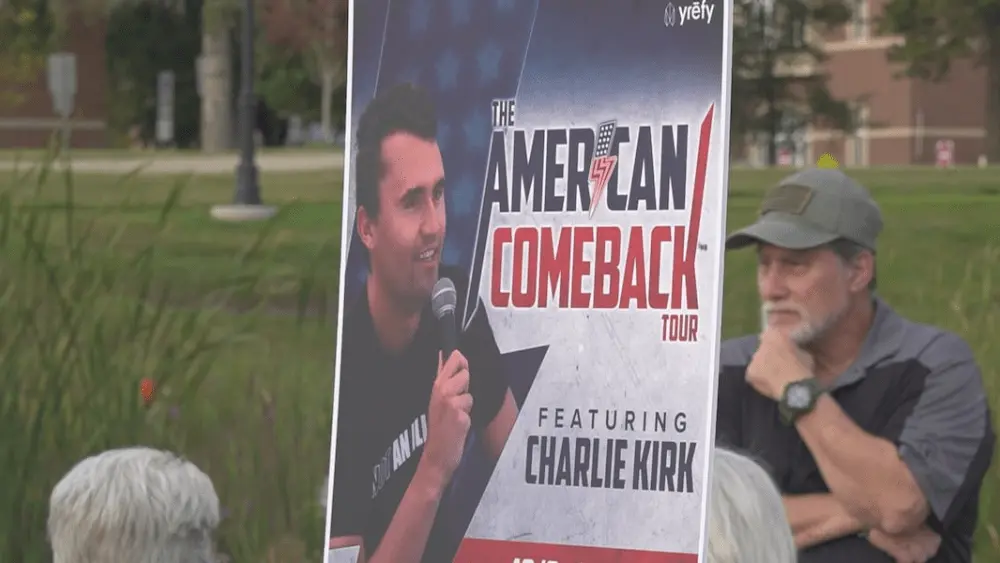 Image of man holding Charlie Kirk poster