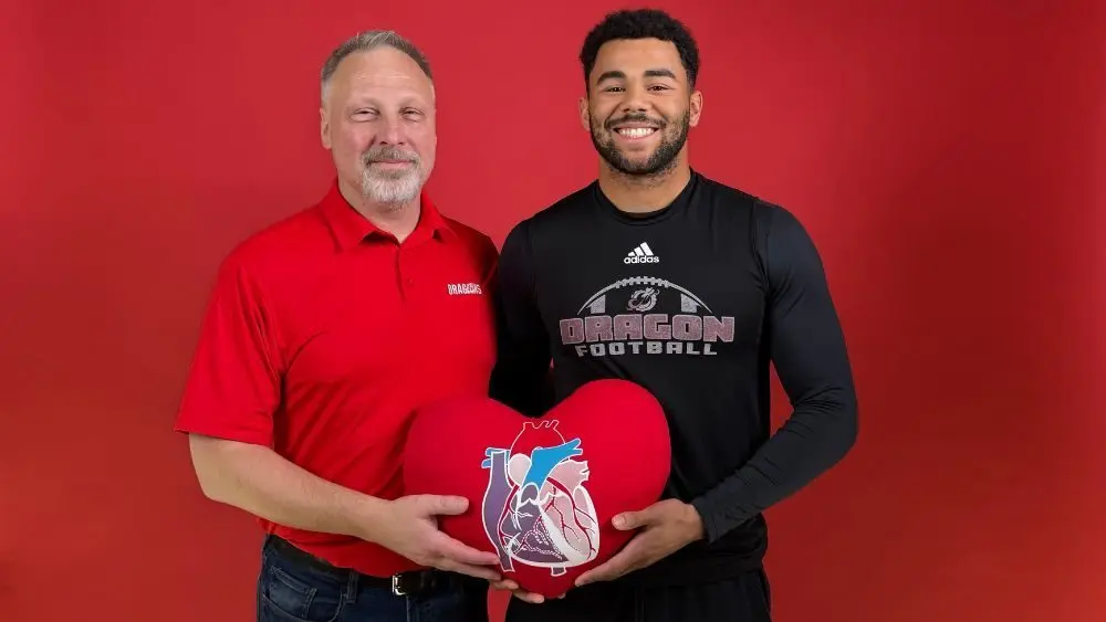 2 guys posing for a photo with a heart pillow