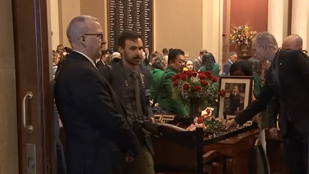 Members of the Minnesota Senate and House of Representatives laying roses on former Speaker of the House Melissa Hortman's desk