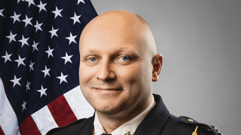 a man in a suit in front of a flag