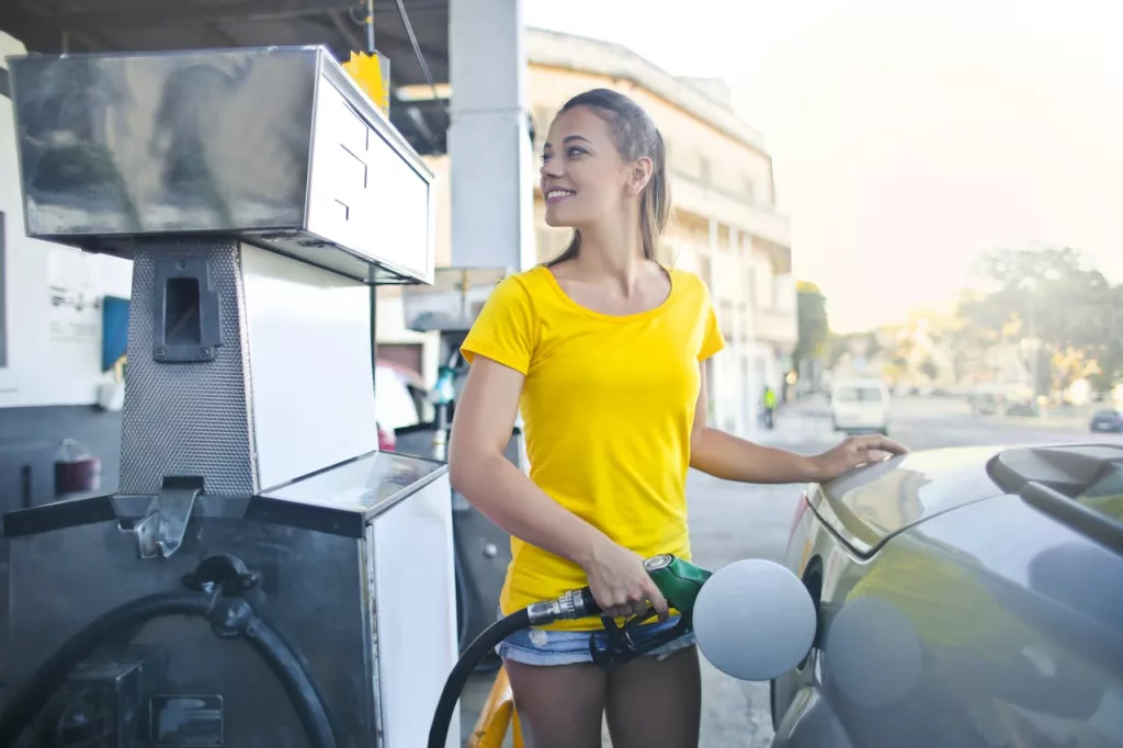 Photo shows teen pumping gas at gas station.