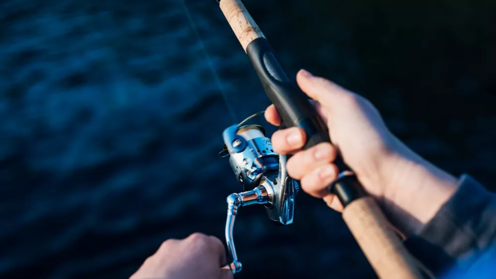Photo shows angler holding rod and reel.