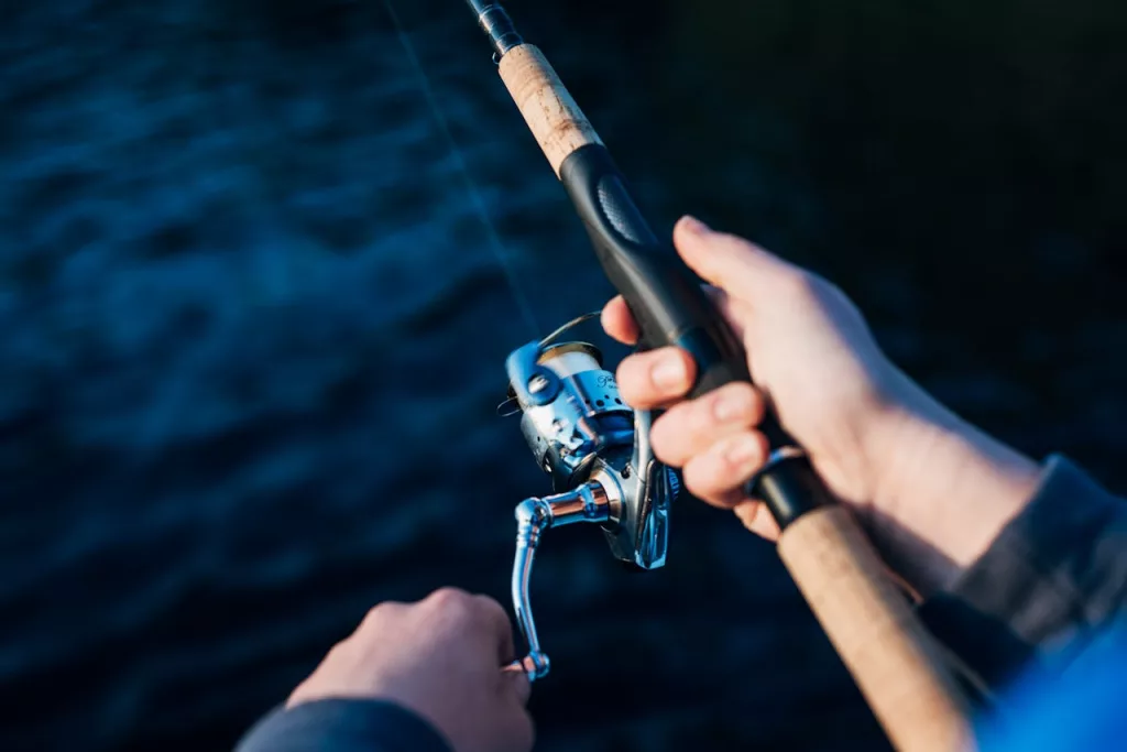 Photo shows angler holding rod and reel.