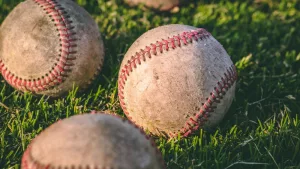 Three baseballs laying in the grass