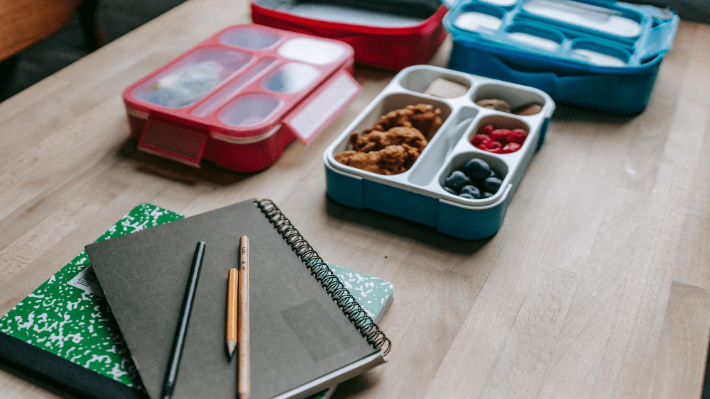 Stock Image of lunch boxes next to notebooks