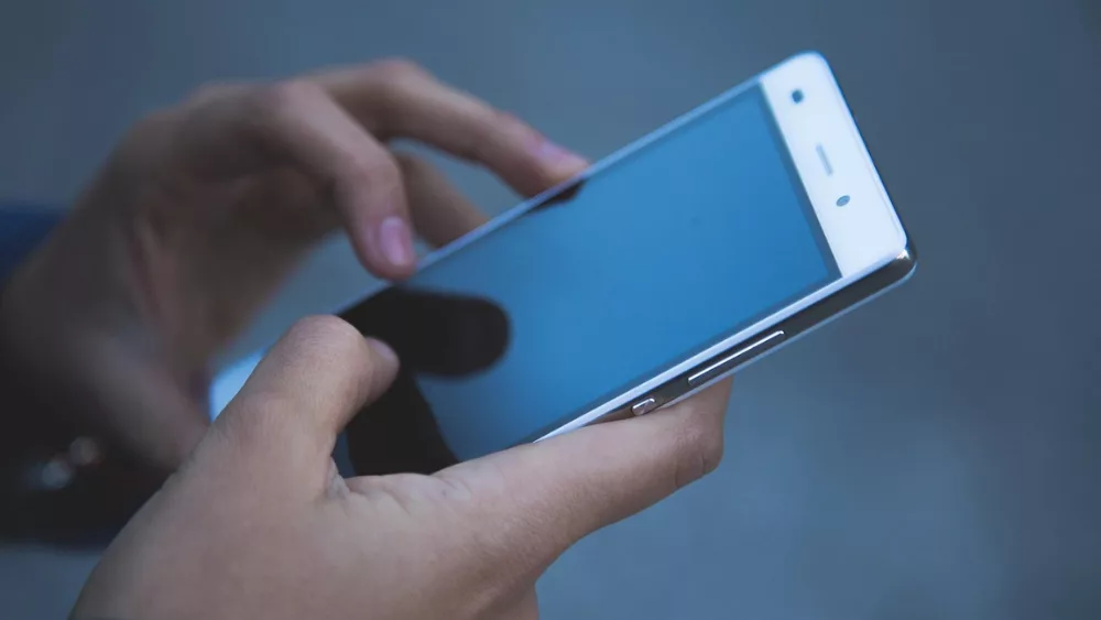 Image of someone holding a phone (hands only)